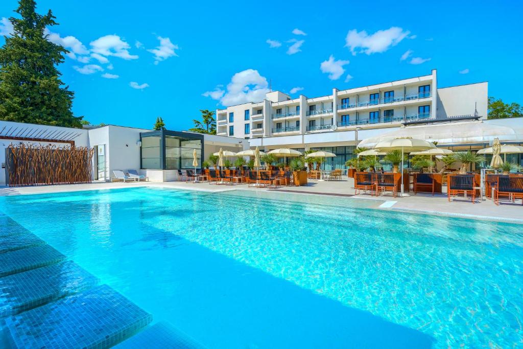 a swimming pool with chairs and umbrellas in front of a hotel at Hotel Alkar - Family Friendly Hotel with Pool in Sinj, Dalmatia in Sinj