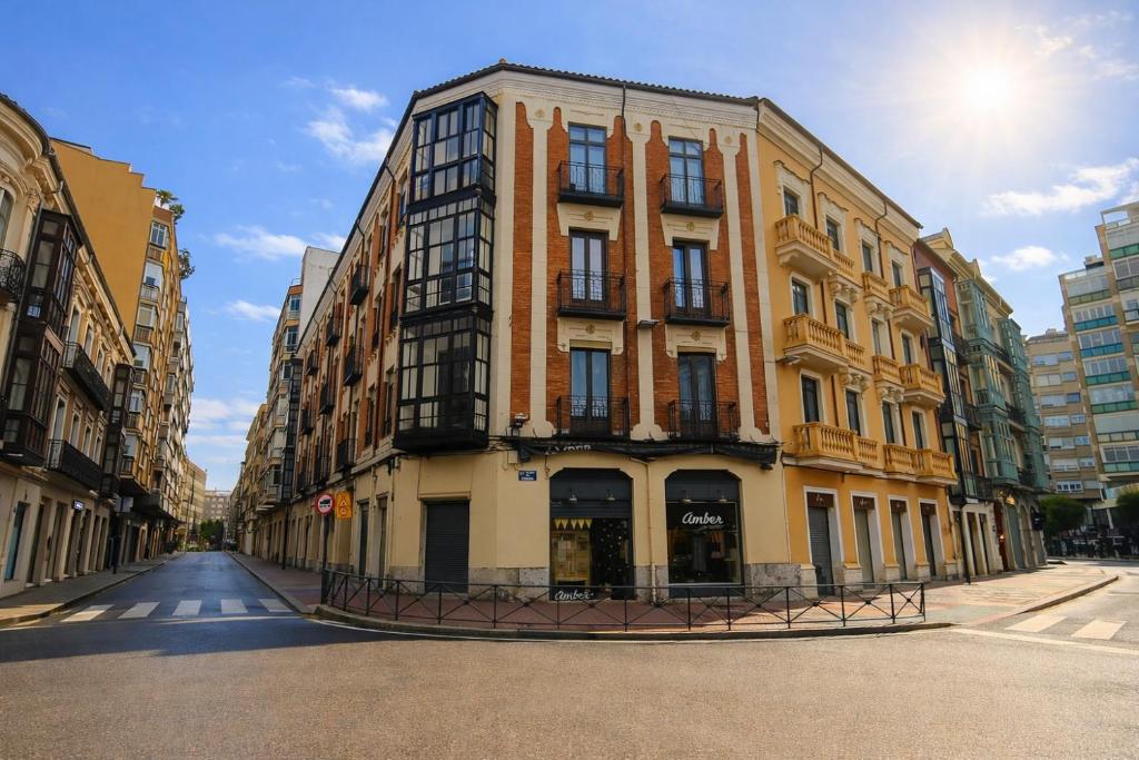 a tall yellow building on a city street at Ele GuestHouse Plaza de España in Valladolid