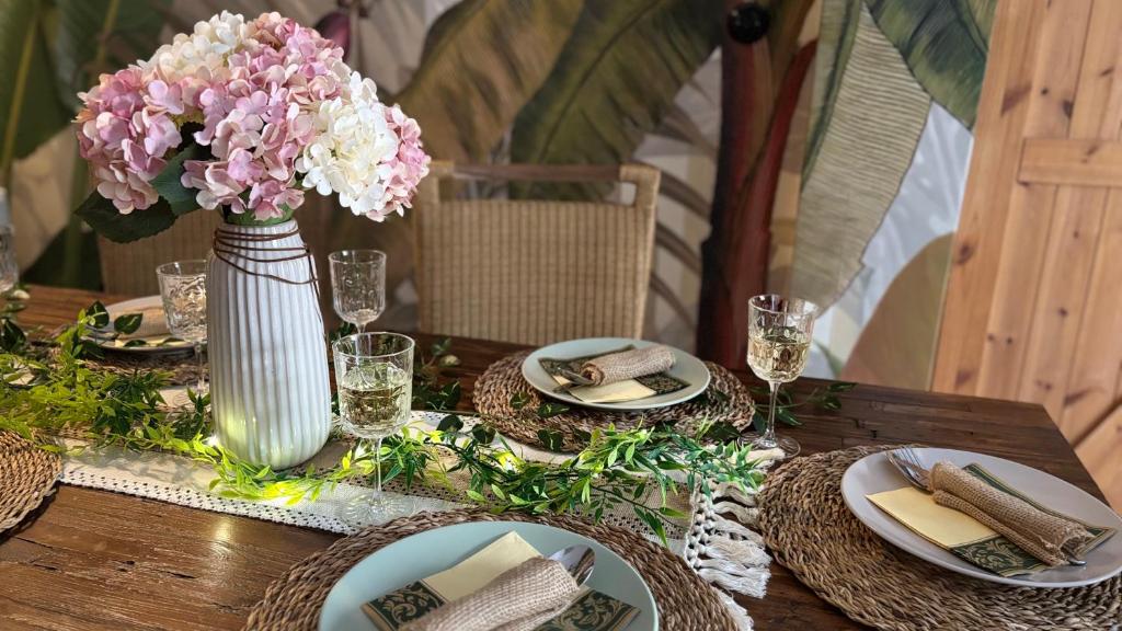 a wooden table with plates and a vase of flowers at Tanny Boho Housy na pešej zóne in Piešťany