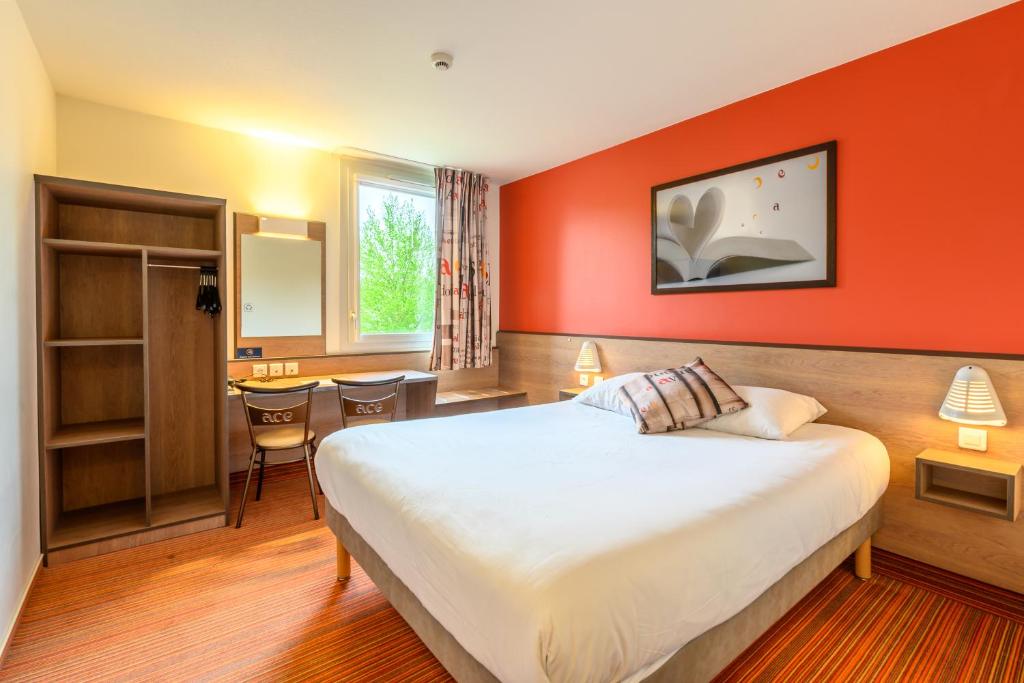 a hotel room with a large bed with an orange wall at Ace Hotel Roanne in Mably