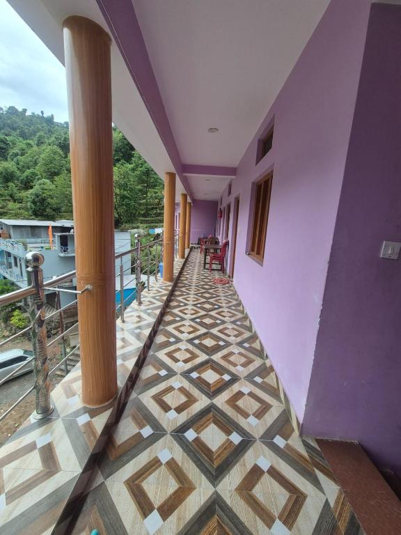 Ein Flur in einem Gebäude mit violetten Wänden und Fliesenboden in der Unterkunft Devom Guest House in Phata