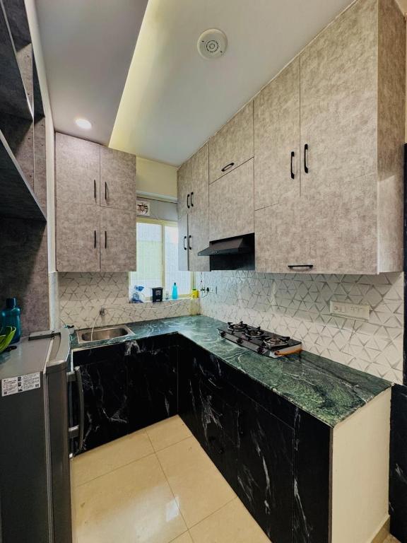 a kitchen with a black counter top and white cabinets at Dream Residency in Karnal