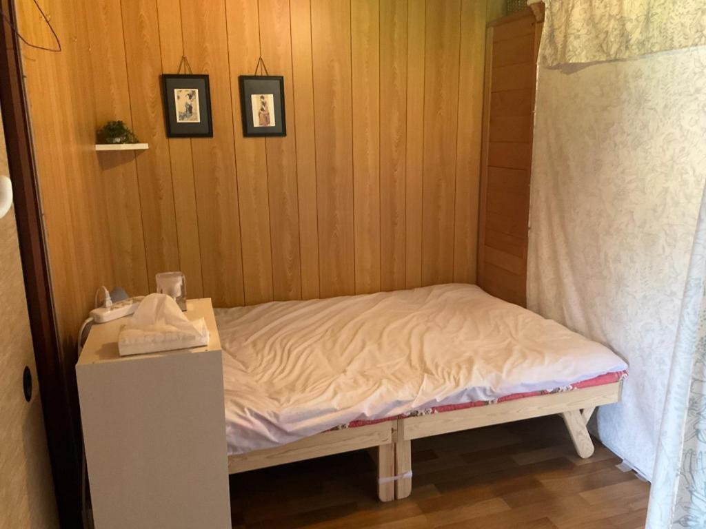 ein kleines Bett in einem Zimmer mit zwei Bildern an der Wand in der Unterkunft Nabiki in Hongu
