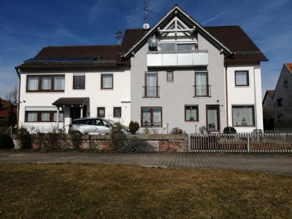 a white house with a car parked in front of it at Pension Merkle in Ichenhausen