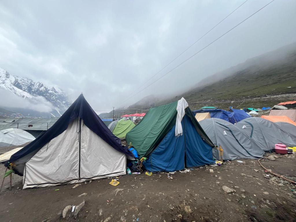 a group of tents in a field with mountains at The Kedar Stay in Kedārnāth