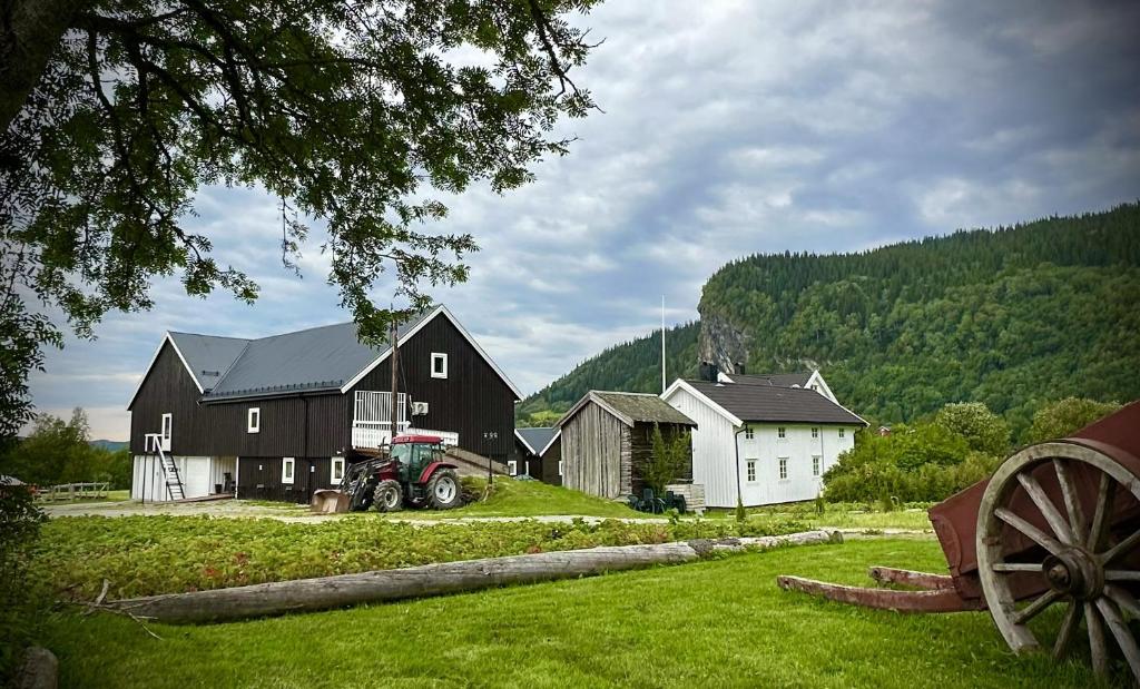 a farm with buildings and a tractor in a field at Låven Parsellhage in Hoset