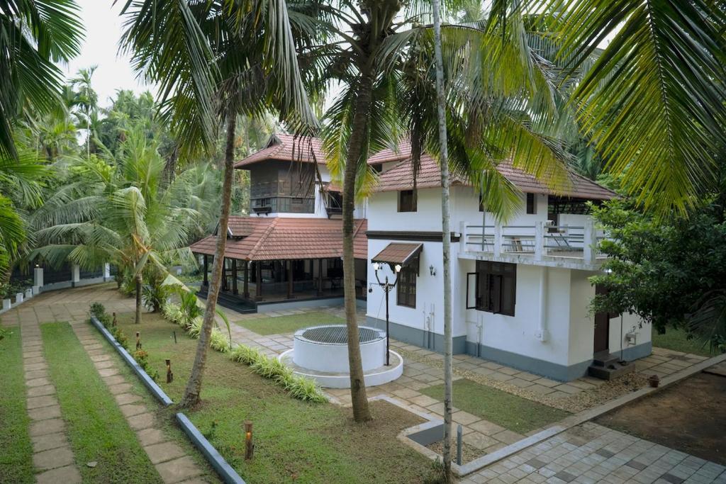 a building with palm trees in front of it at Poomuttathillam in Kunnamangalam