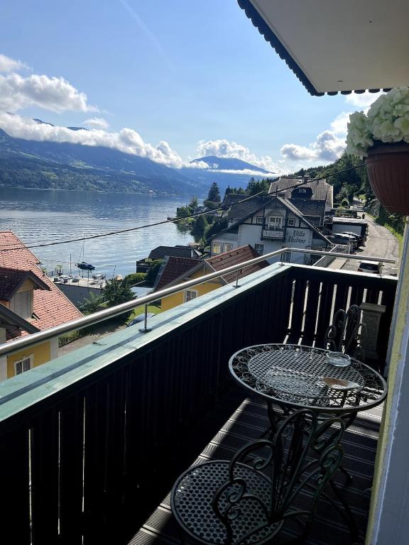 a table on a balcony with a view of the water at Chic & Cozy Lake View Apartment in Seeboden