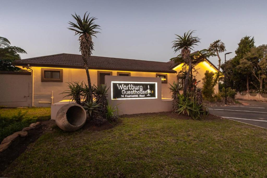 a sign in front of a house with palm trees at Wartburg Guesthouse in Wartburg