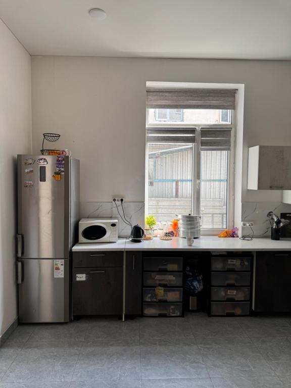 a kitchen with a stainless steel refrigerator and a window at Abay Hostel in Almaty