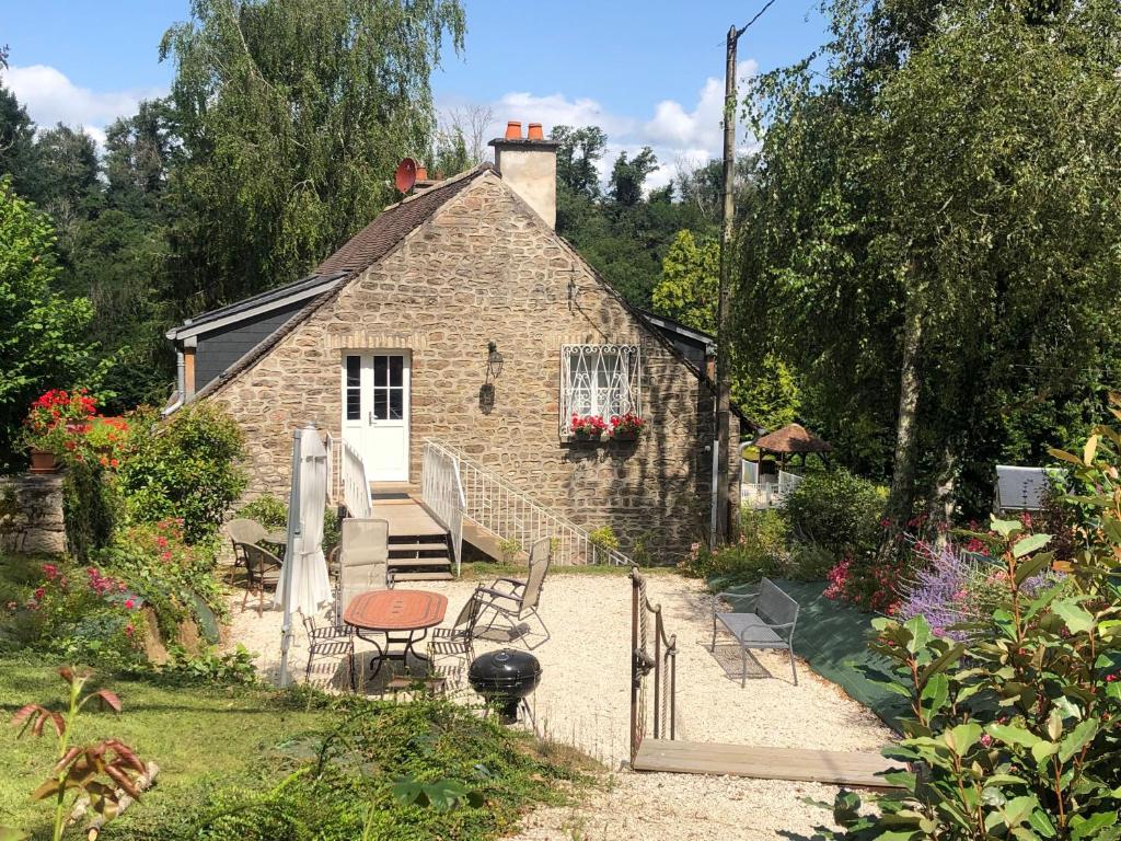 a stone house with a table and chairs in front of it at Le Mariotte in Pont-et-Massène
