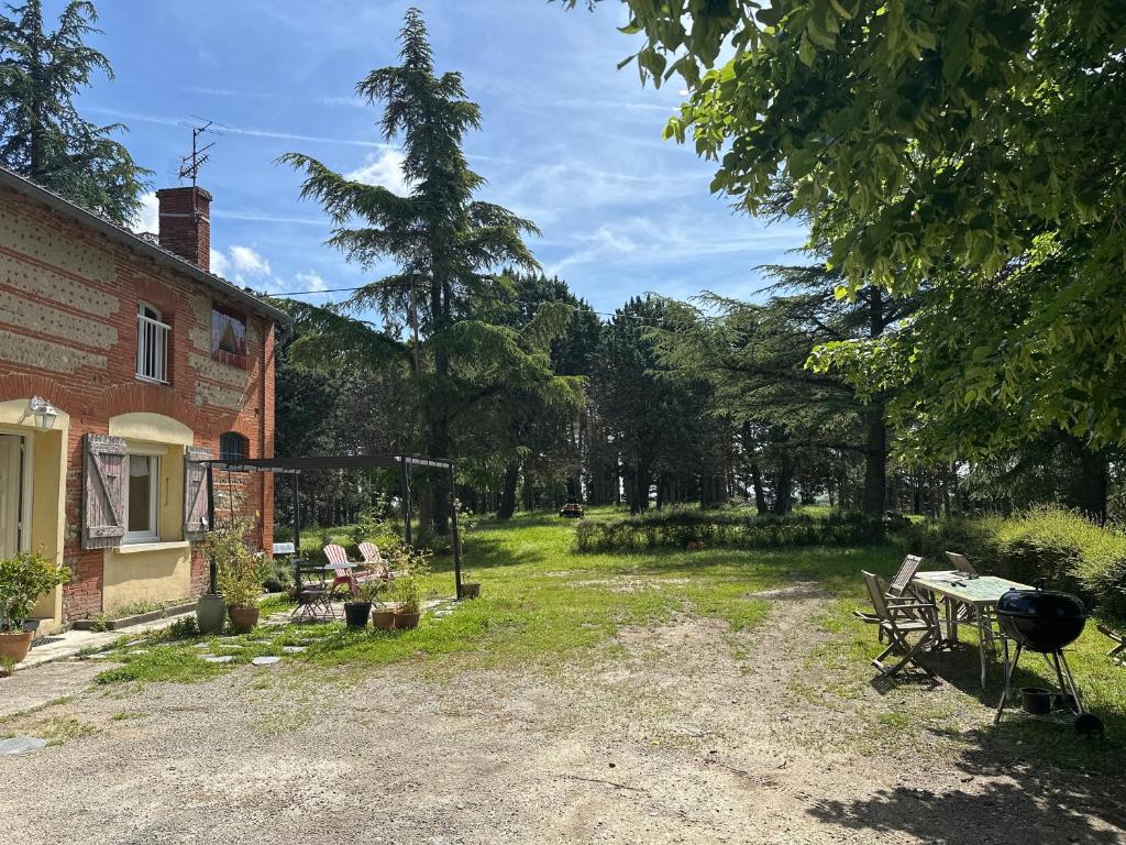 a backyard of a house with a grill and chairs at Hébergement TRAVAILLEURS in Monestrol