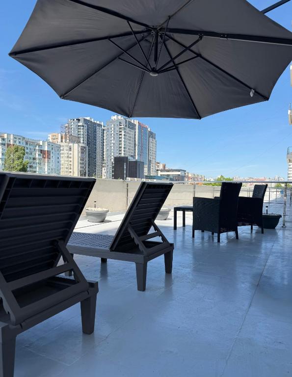 two chairs and a table with an umbrella on a patio at Boulevard terrace apartment in Chişinău
