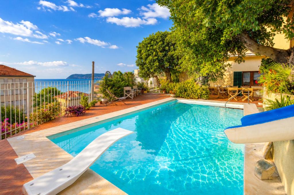 a swimming pool with a slide in front of a house at Hostdomus - Villa Gabriella with private pool in Alassio