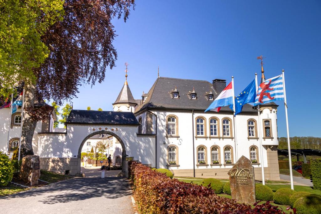a building with three flags in front of it at Chateau d'Urspelt in Urspelt