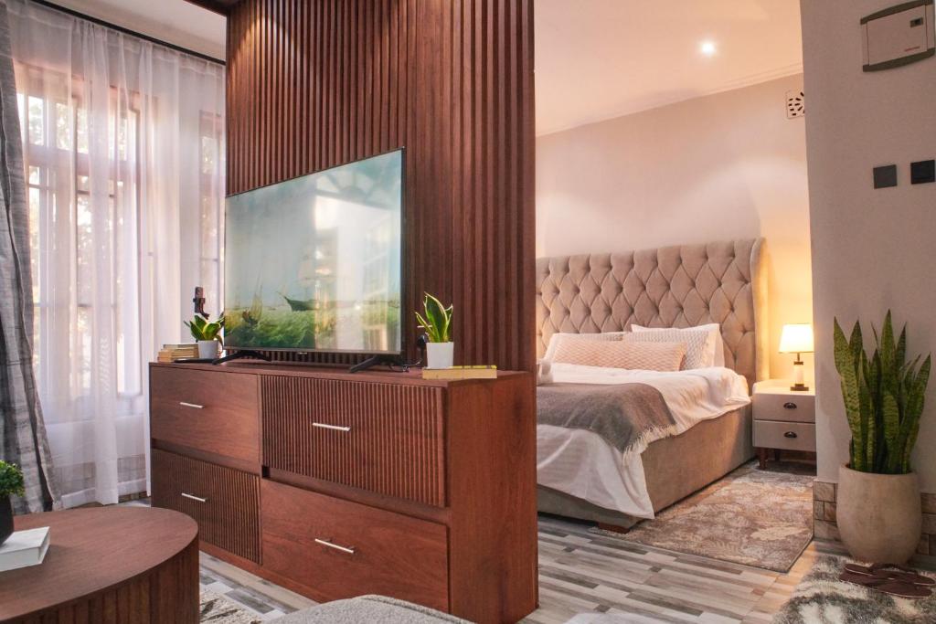 a bedroom with a bed and a dresser with a television on it at Bustani Home Studio in Arusha