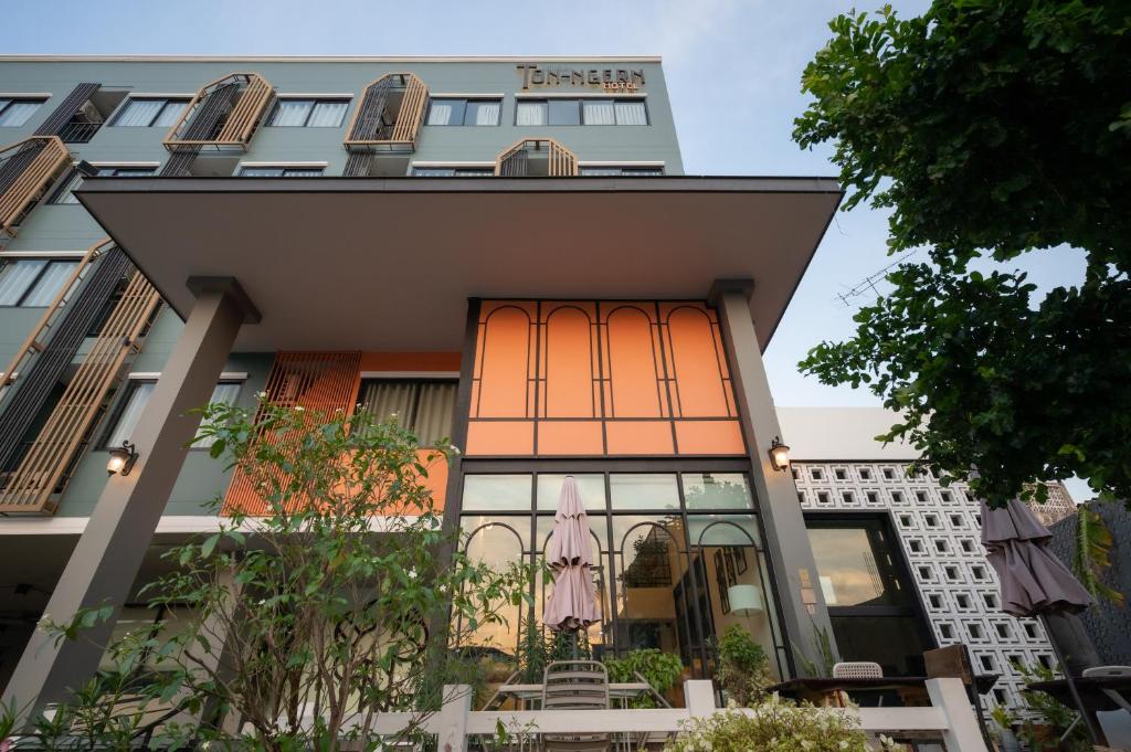 a building with an orange facade with a pink umbrella at โรงแรมต้นเงิน in Khon Kaen