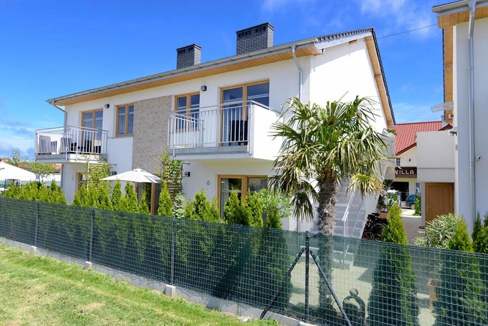 a white house with a palm tree in front of it at Chmielowa2 - Apartamenty in Rowy