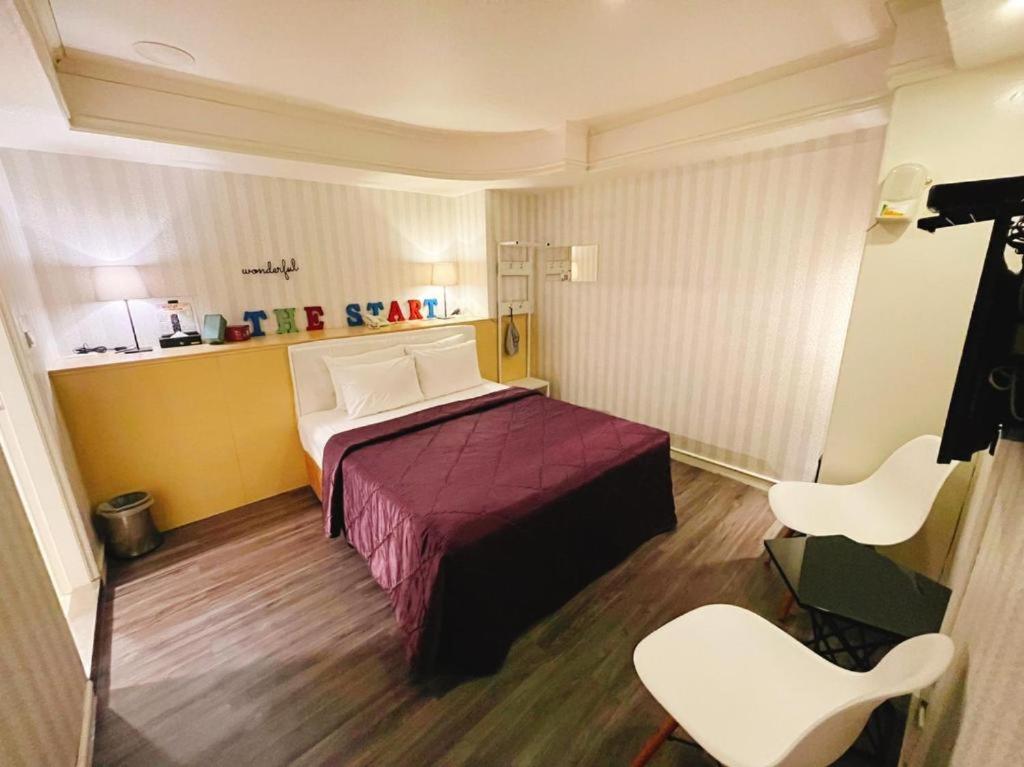 a small room with a bed and two chairs at Joy Garden Hotel in Kaohsiung
