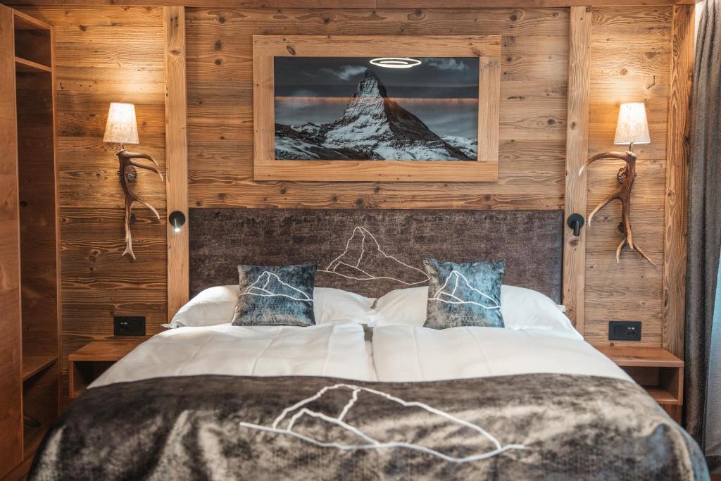 a bedroom with a bed with a mountain picture on the wall at La Perle Apartments in Zermatt
