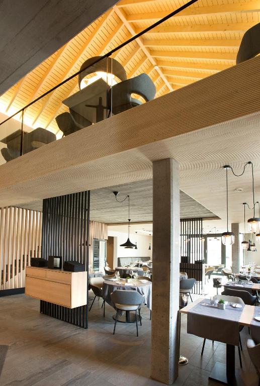 a dining room with tables and chairs and wooden ceilings at Hostellerie Stafelter in Walferdange