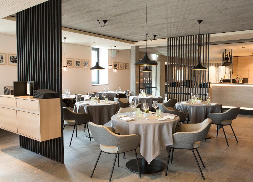 a dining room with tables and chairs and lights at Hostellerie Stafelter in Walferdange