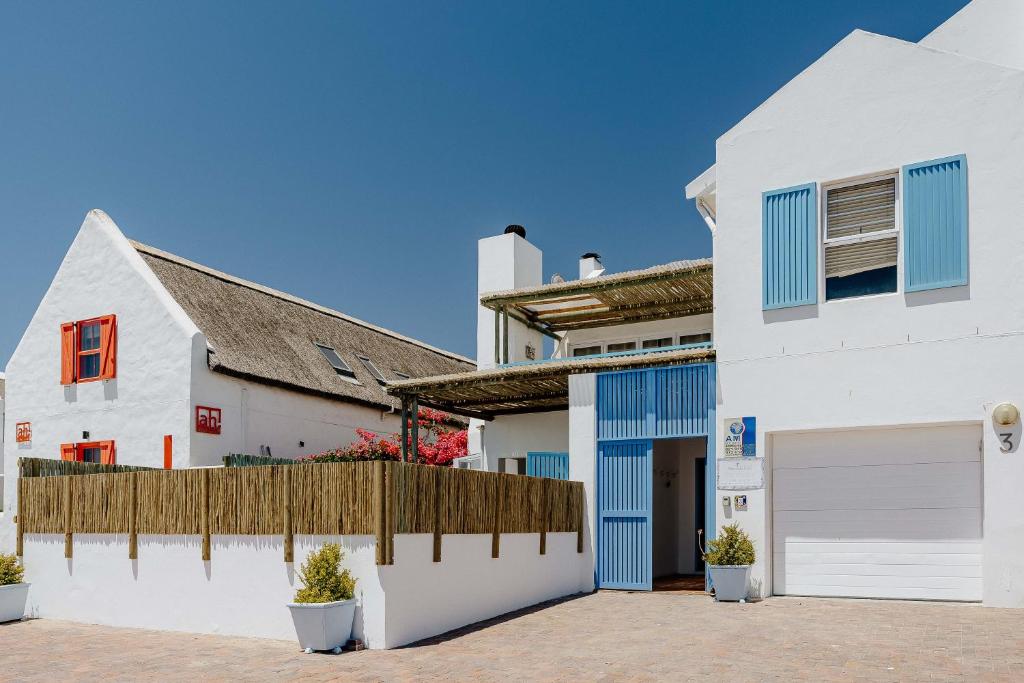 a white house with blue doors and a fence at Sterretjie in Paternoster