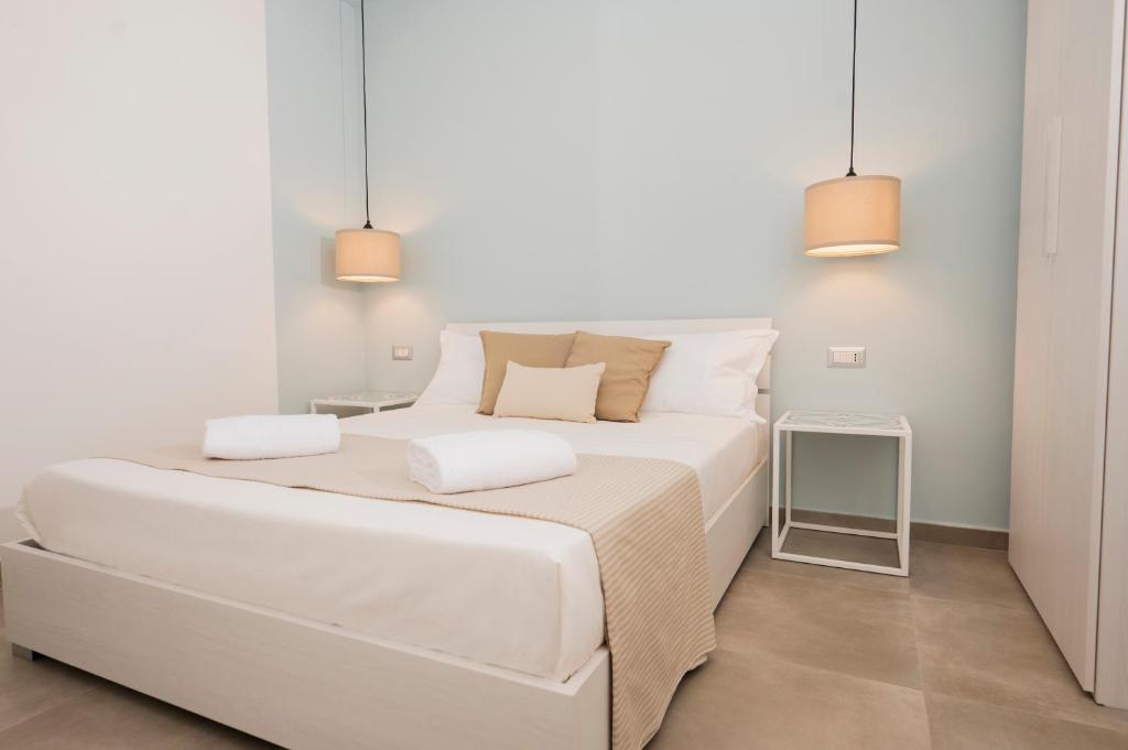 a white bedroom with a large white bed and two lights at Zest House Pompei in Pompei
