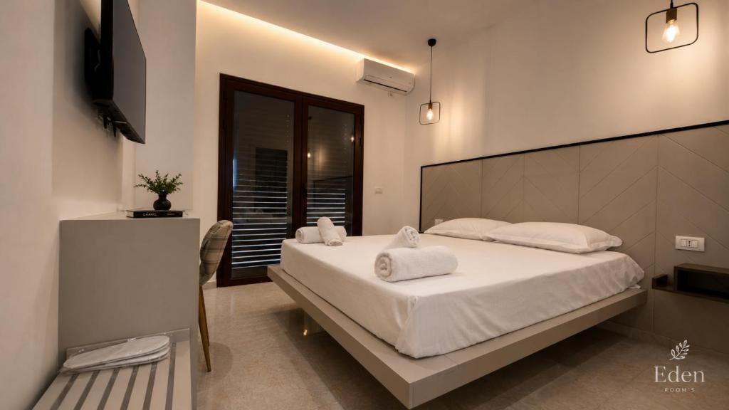 a bedroom with a large bed with white sheets and pillows at Eden Rooms in Vlorë