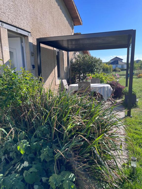 a patio with a table and chairs under a pergola at GITE DE MIRAUVILLE in Apremont-la-Forêt