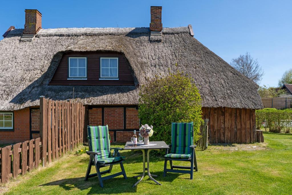 a table and chairs in front of a thatched house at Alte Dorfstraße 29 REETungsinsel in Behrensdorf