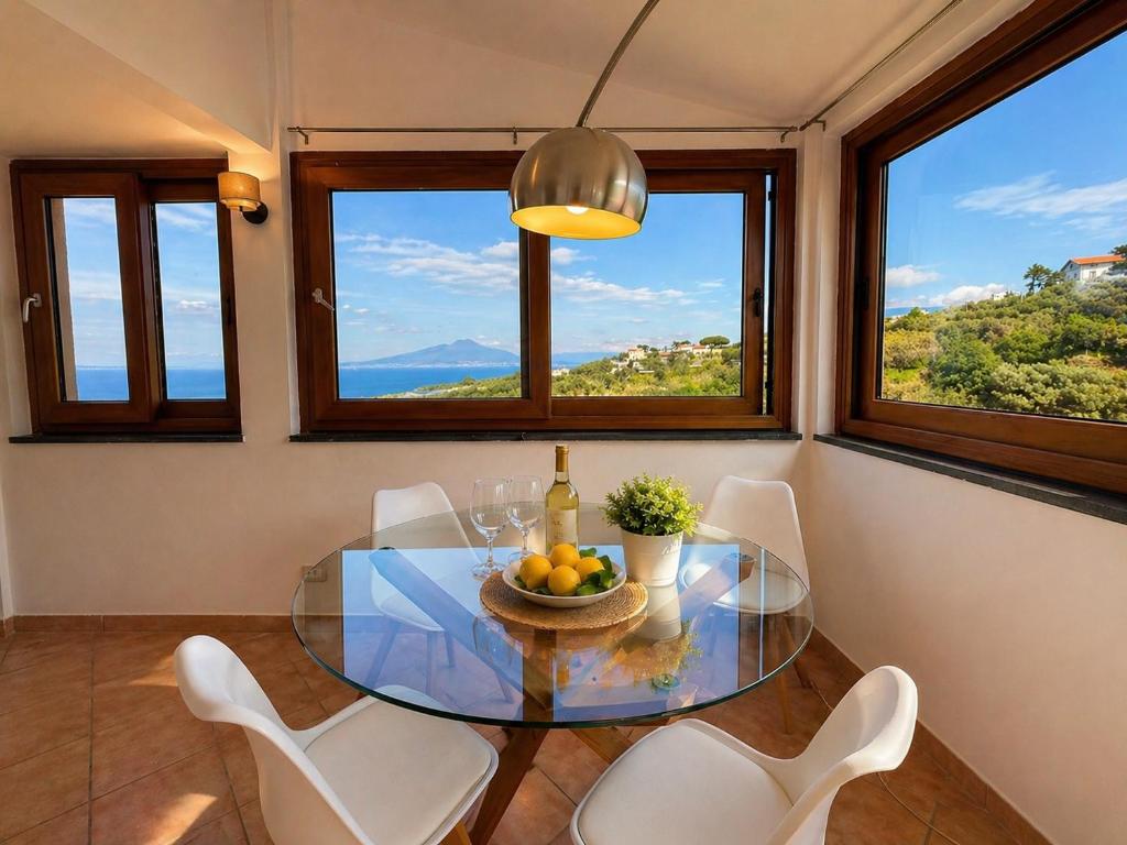 a dining room with a glass table and white chairs at Villa Rosmary in Massa Lubrense