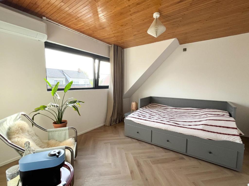 a bedroom with a bed and a chair and a window at PS Casa in Hasselt