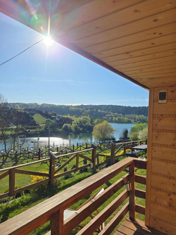 a view from the porch of a cabin with a fence and a lake at Dobra Miejscówka Domki nad Jeziorem Solińskim Jacuzzi 60 m od plaży 504-978-418 in Zawóz