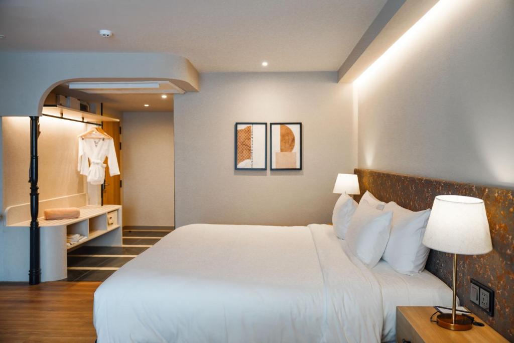 A warmly lit guest room with a large bed, open wardrobe and compact dressing area.