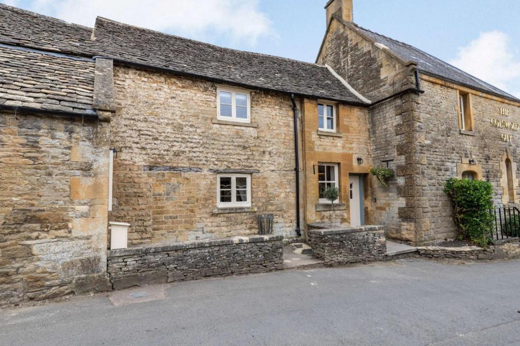 an old stone house with a driveway in front of it at The Cotswold Lady in Guiting Power