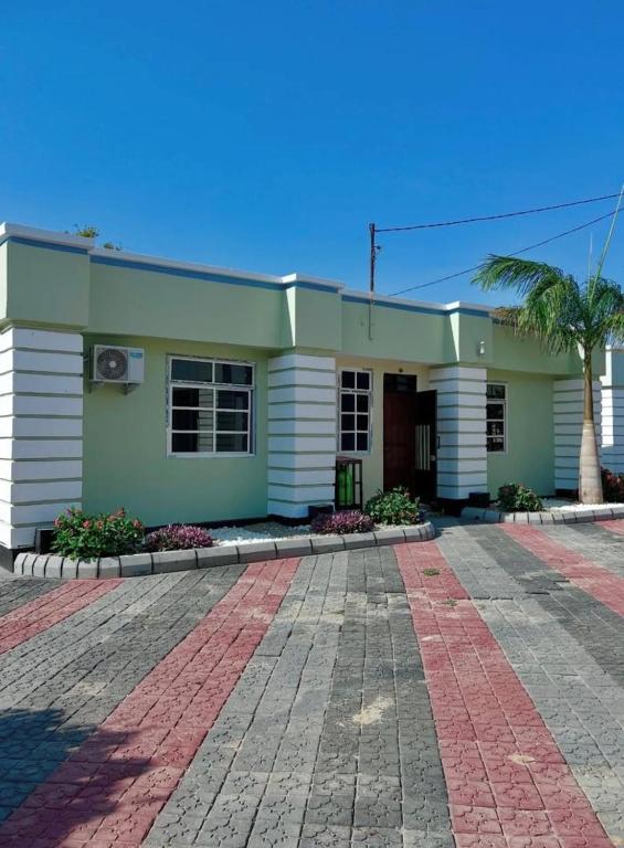 a green and white house with a palm tree at Kamur Homes Apartment in Dodoma