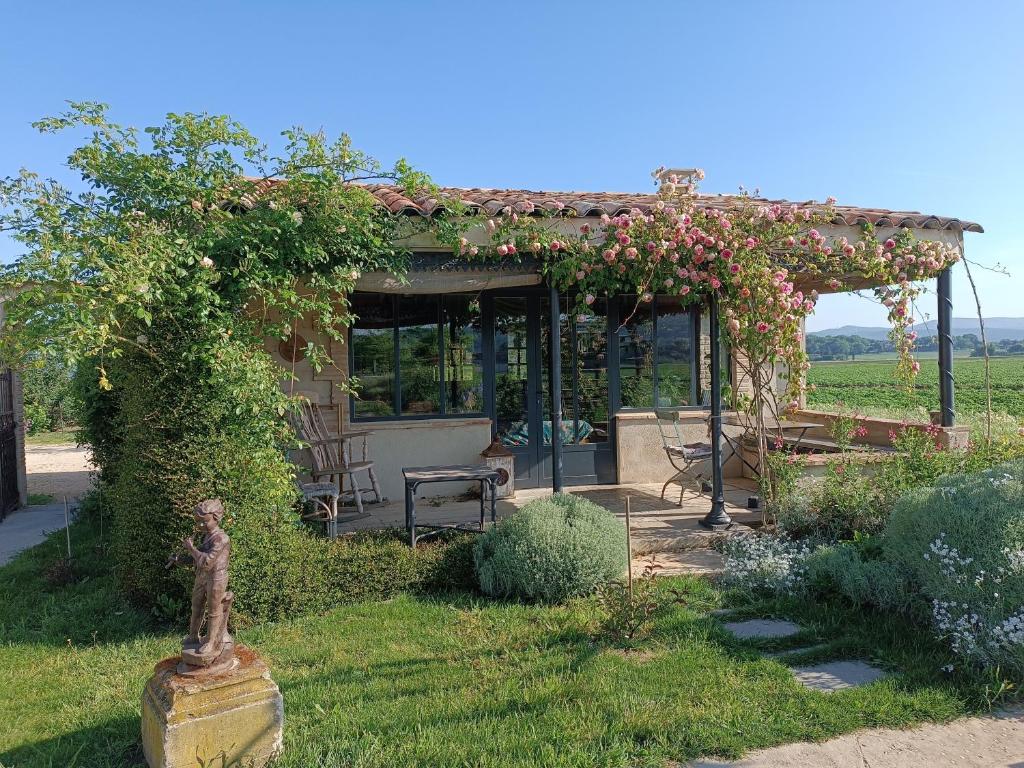 a garden with a pergola with a bench and roses at La Bohême La Belle Etoile Petit déjeuner compris in Charols