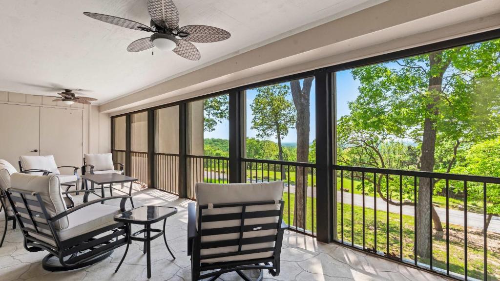 a screened in porch with chairs and a ceiling fan at Lake Ozark Oasis Central Location & Pool Access in Lake Ozark