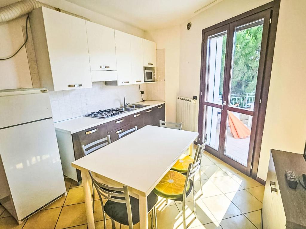 a kitchen with a white table and a white refrigerator at Apartment Mairen-3 by Interhome in Rosolina Mare