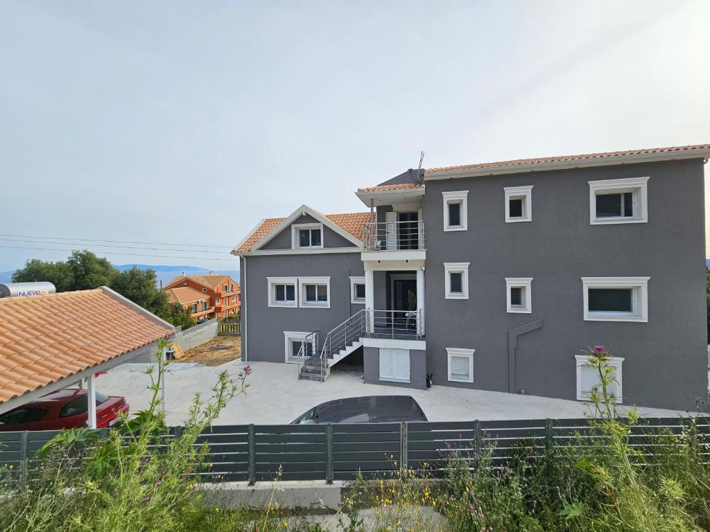 a gray house with a car parked in front of it at Zeus Cosmos Apartments in Lourdata