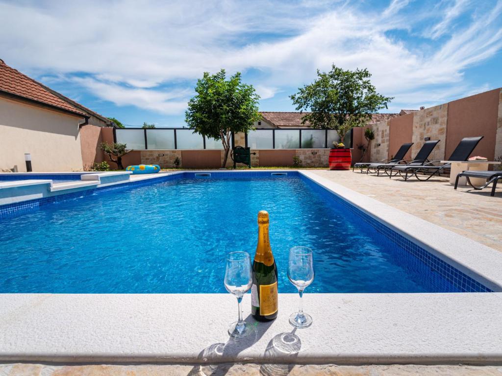 a bottle of wine and two wine glasses next to a swimming pool at Holiday Home Šimić by Interhome in Dušić