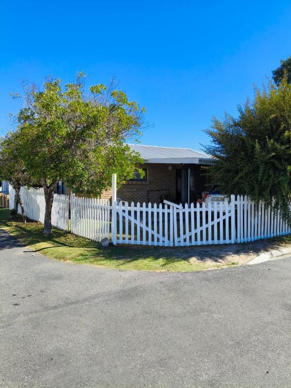 a white picket fence in front of a house at Sea Wave Cottage in Pearly Beach