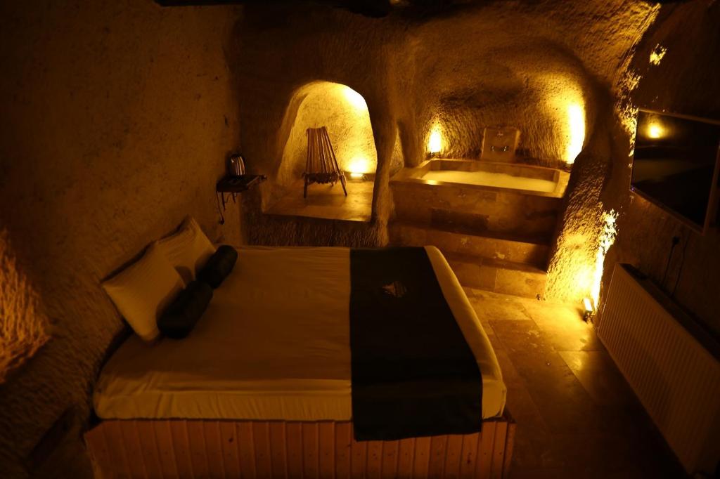 a bedroom with a bed in a cave with lights at Rock Mansion Cappadocia in Nar