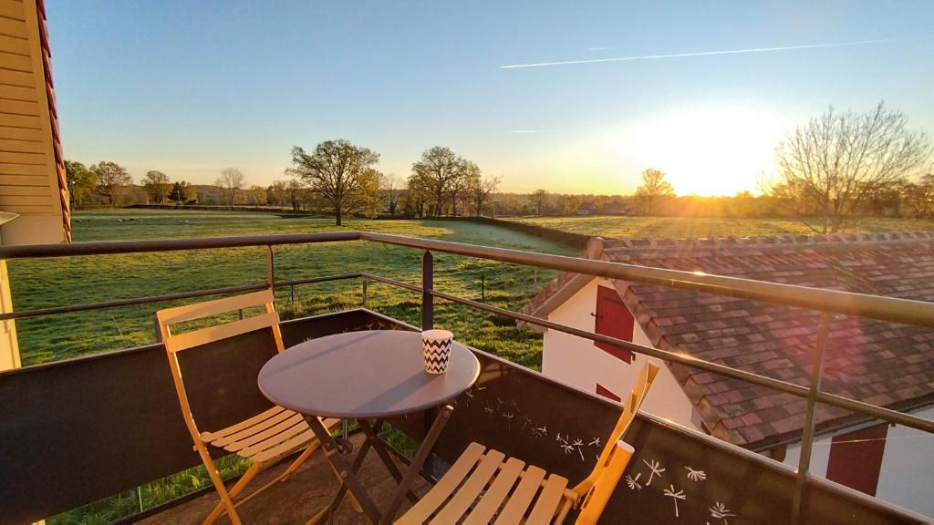 a balcony with a table and chairs and a field at Maison cosy au calme à 15 min du Pal - l'Ecole Buissonnière in Saligny-sur-Roudon