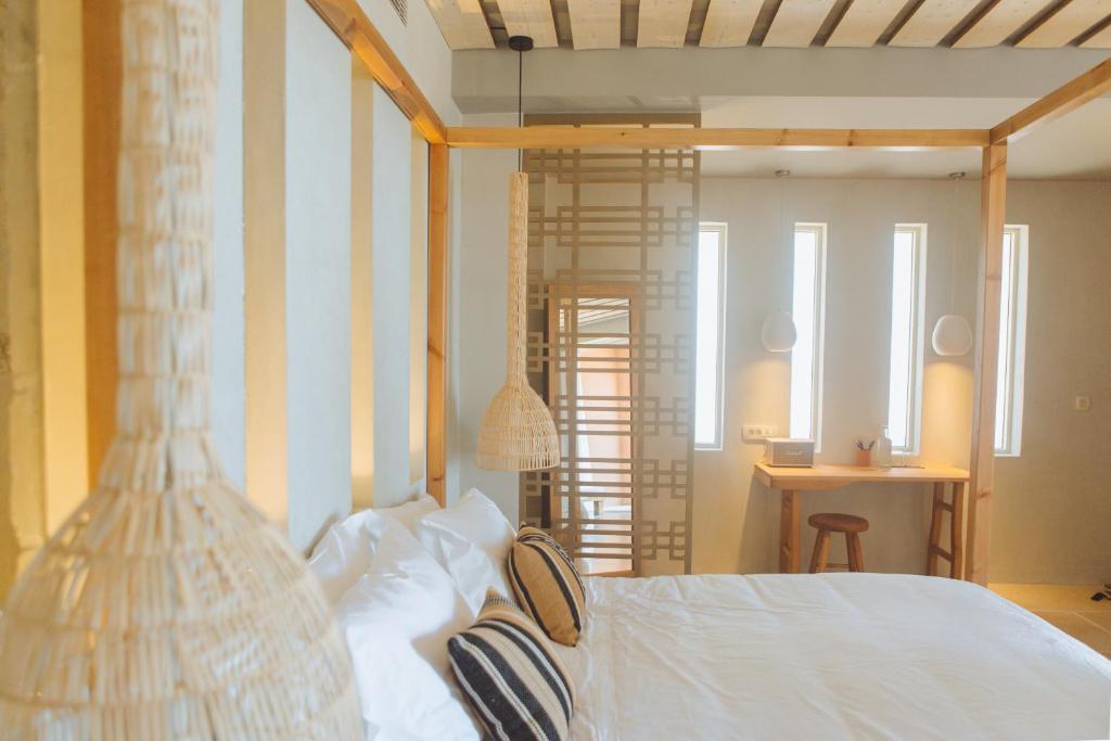 a bedroom with a white bed with a striped wall at The Theodore Boutique Hotel- adults only 16 plus in Agia Marina Nea Kydonias