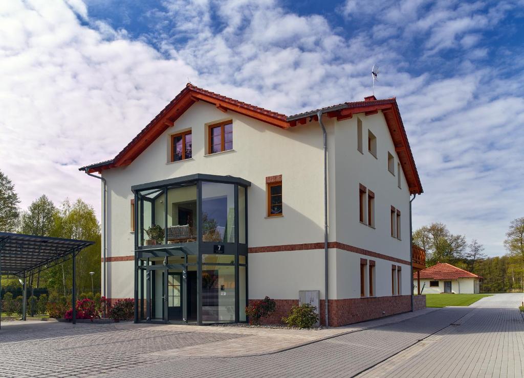 a large white building with glass windows on a street at Lipowa Przystań in Tarnów Jezierny