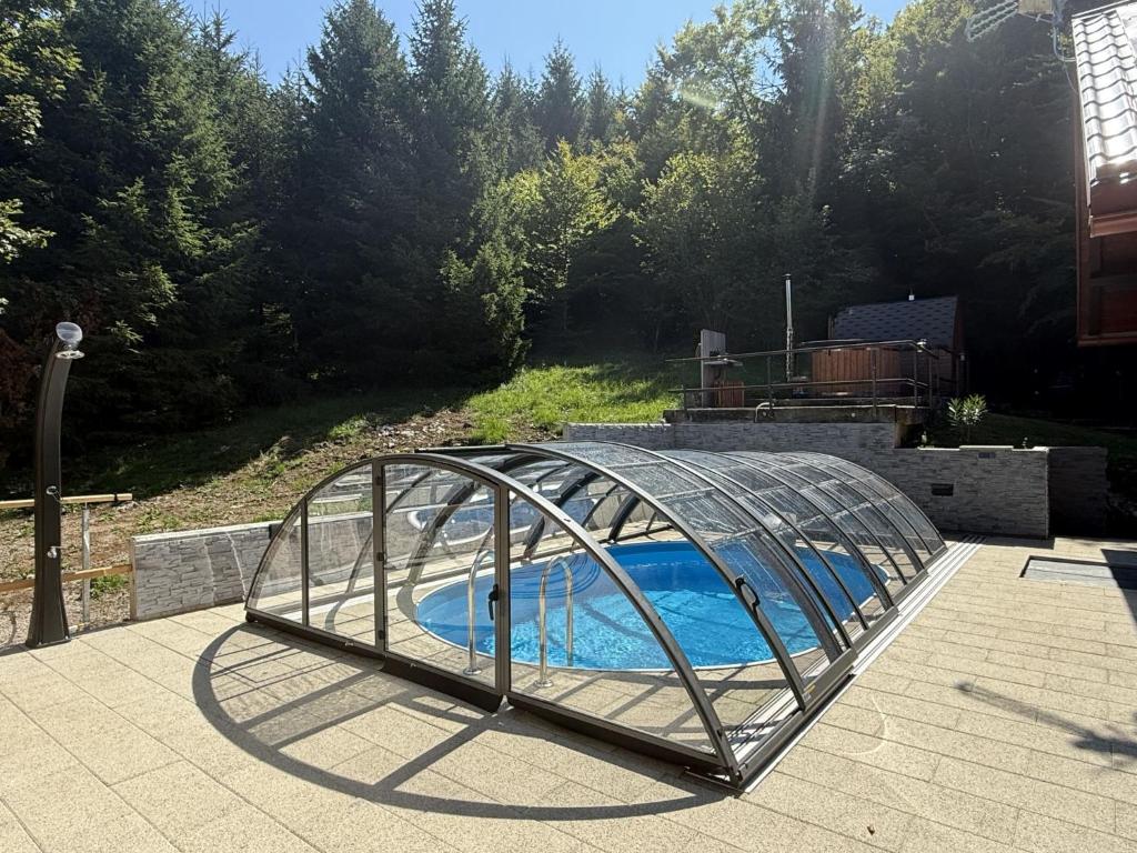 a glass greenhouse over a swimming pool in a yard at Chalet Cozy Bear Cabin by Interhome in Mrkopalj