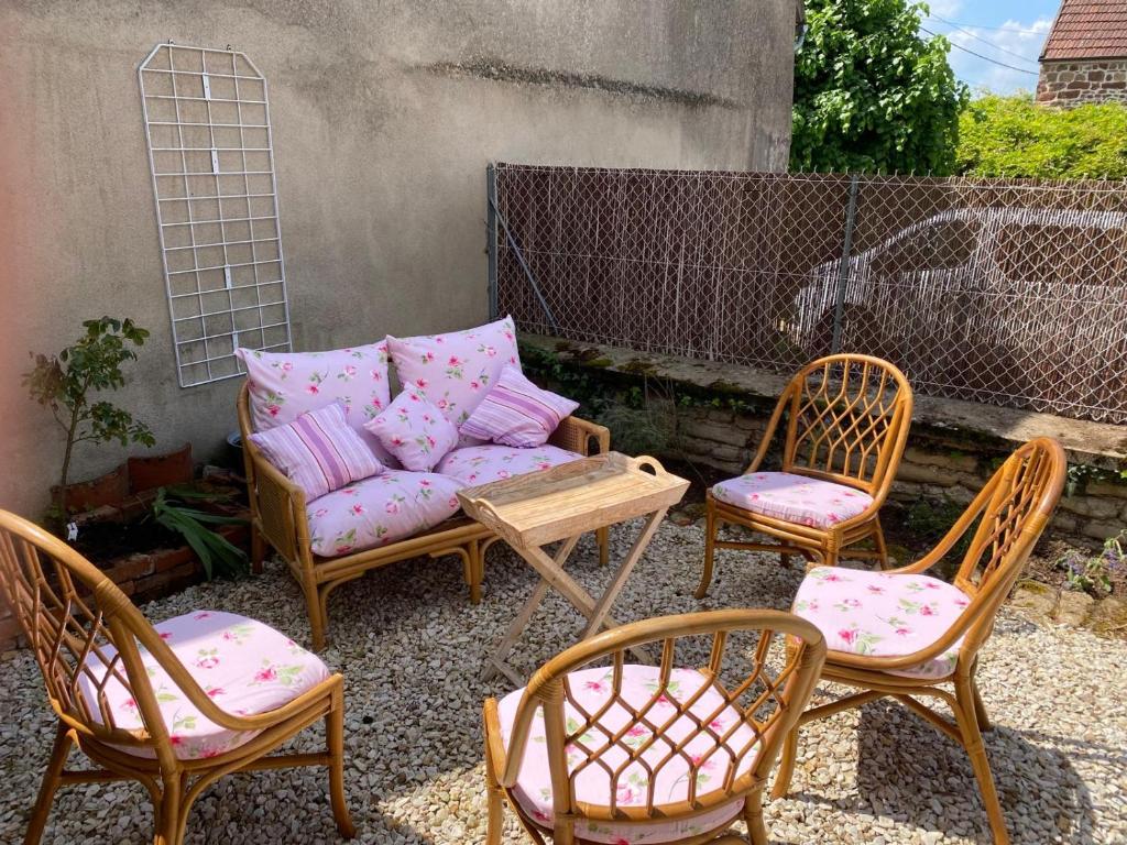 a patio with three chairs and a couch with pillows at Gite Simon in Guillon
