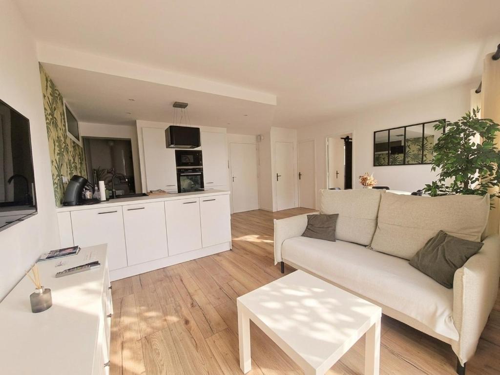 a living room with a white couch and a kitchen at Liv'in Saint Seb, proche de Nantes in Saint-Sébastien-sur-Loire